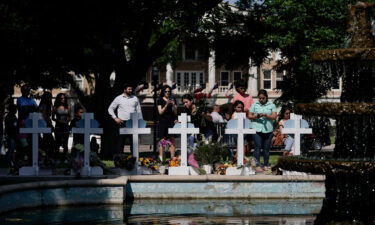 People pay their respects at a memorial site for the victims killed in this week's elementary school shooting in Uvalde
