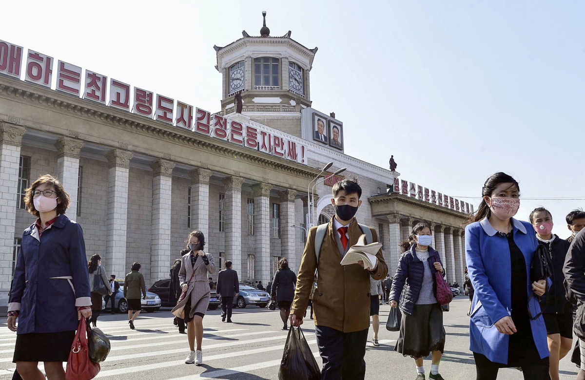 <i>Kyodo/Reuters</i><br/>People wearing protective face masks walk amid concerns over Covid-19  in front of Pyongyang Station in Pyongyang