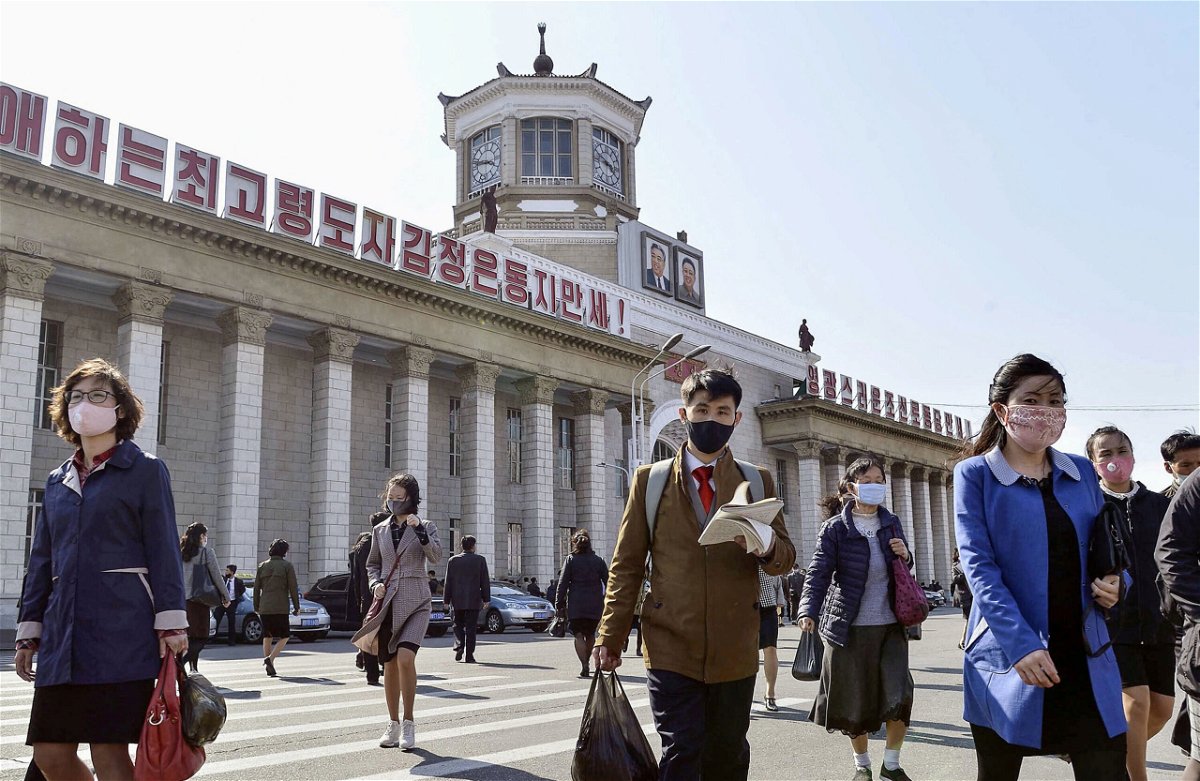 <i>Kyodo/Reuters</i><br/>People wearing protective face masks walk amid concerns over Covid-19  in front of Pyongyang Station in Pyongyang