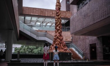 Two children look at the "Pillar of Shame" statue at the Hong Kong University campus on October 15