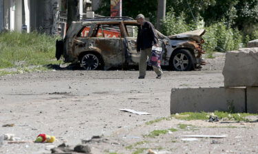 A man walks past the wreckage of a car in Lysychansk on June 21