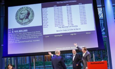 People point to the screen that shows the final price of $103.5 million for Russian journalist Dmitry Muratov's 23-karat gold medal of the 2021 Nobel Peace Prize after being auctioned at the Times Center