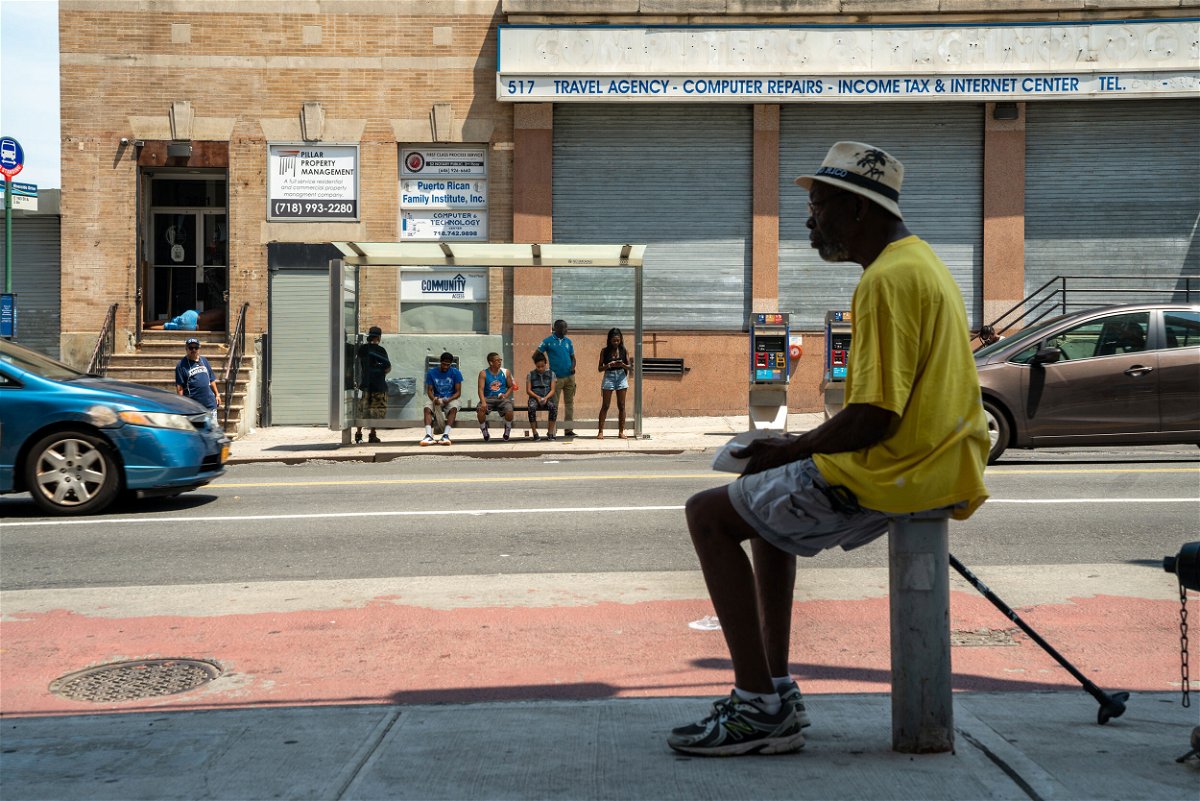 <i>David 'Dee' Delgado/Bloomberg/Getty Images</i><br/>A man sits in the shade a people wait at a bus stop in the Bronx borough of New York