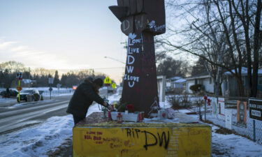 Michelle Filkins cleans up and lights candles at the Daunte Wright memorial after guilty verdicts were announced against former police officer Kimberly Potter on December 23
