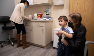 Ilana Diener (right) holds her 3-year-old son during a Moderna Covid-19 vaccine trial on November 30