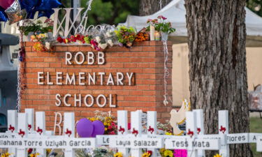 A memorial is seen surrounding the Robb Elementary School sign following the mass shooting at Robb Elementary School on May 26 in Uvalde