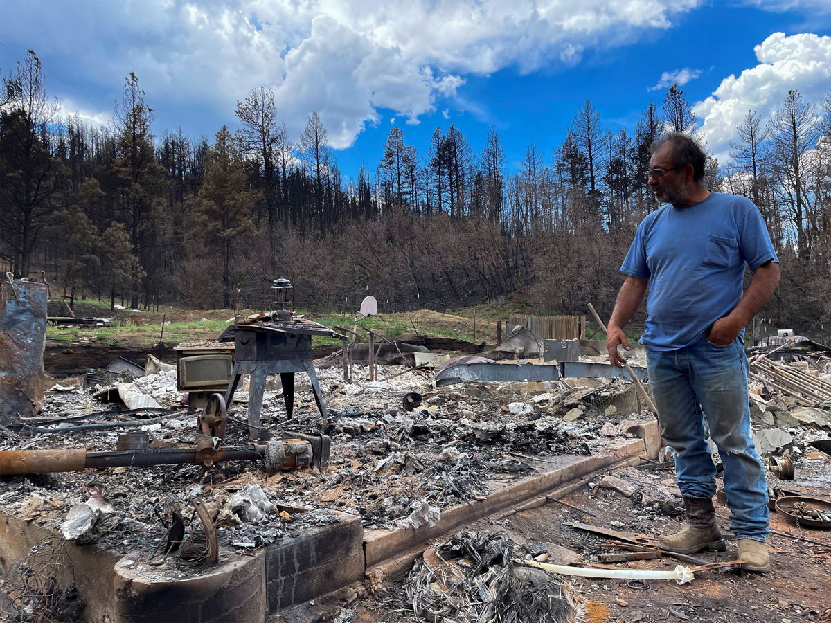 <i>Andrew Hay/Reuters</i><br/>Daniel Encinias stands next to the ruins of his home