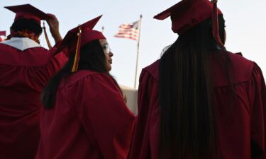 A US flag flies as students earning degrees at Pasadena City College participate in the graduation ceremony