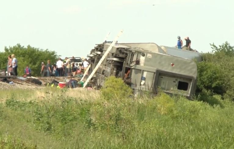 People stand outside a derailed Amtrak passenger train Monday, June 28, 2022, near Mendon, Missouri. Two people on the train died in the crash with a dump truck.