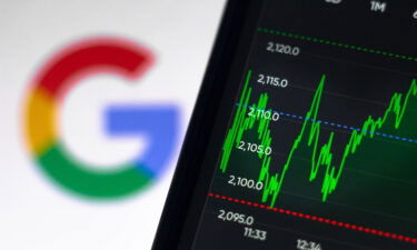 In this photo illustration the stock market graphic of Google seen displayed on a smartphone with a Google logo in the background.