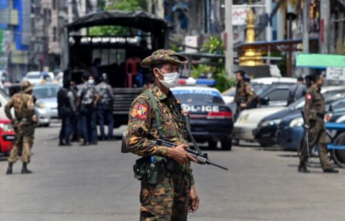A soldier stands guard along a road as security forces search for protesters in Yangon.