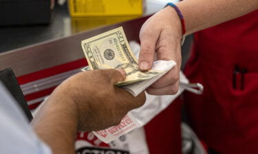 A customer pays cash for a purchase at a store in Merced