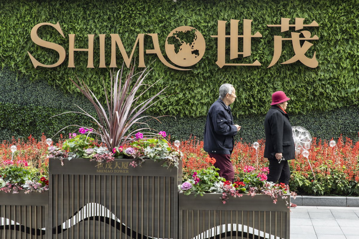 <i>Qilai Shen/Bloomberg/Getty Images</i><br/>An elderly couple walk past a sign in front of Shimao Tower