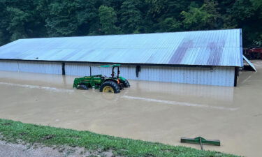 A barn is seen submerged in floodwaters. Behind it was where Asher's home