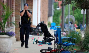 A Lake County police officer walks down Central Ave in Highland Park on Monday.