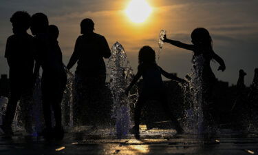 Children cool off by playing in a fountain in Domino Park