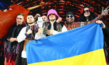 Members of the band Kalush Orchestra pose onstage with the winner's trophy and Ukraine's flags after winning on behalf of Ukraine the Eurovision Song Contest in May. The UK will host next year's Eurovision Song Contest on behalf of Ukraine.