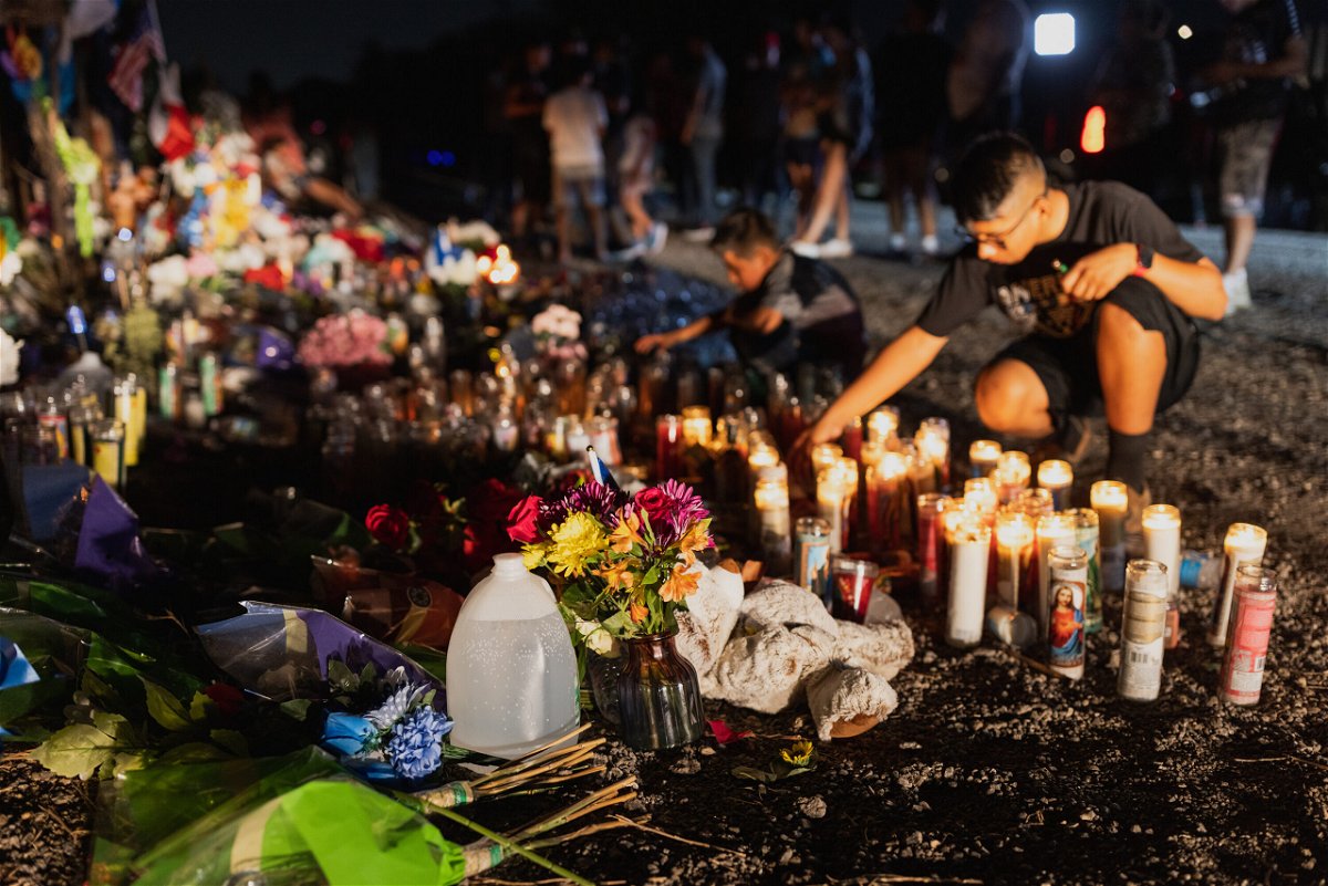 <i>Jordan Vonderhaar/Getty Images</i><br/>Mourners place water bottles at a makeshift memorial for the 53 migrants found dead in a semi-truck on the outskirts of San Antonio