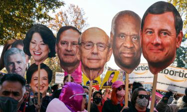 Activists hold photos of U.S. Supreme Court justices in front of the U.S. Supreme Court in December 2021 in Washington