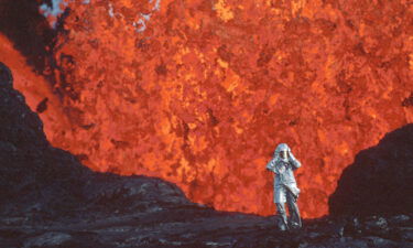 Katia Krafft wearing aluminized suit standing near lava burst at Krafla Volcano