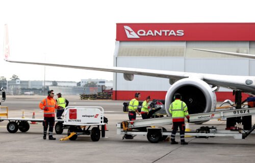 Members of the ground crew work next to an aircraft operated by Qantas Airways Ltd. at Sydney Airport in Sydney