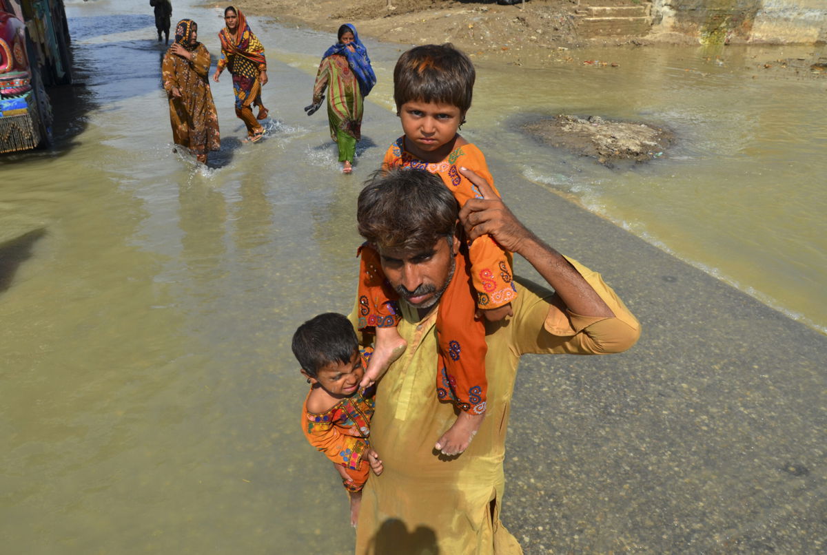 <i>Zahid Hussain/AP</i><br/>A displaced man carries his daughters from his flood-hit home in Jaffarabad