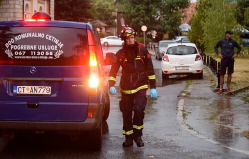 A firefighter walks by a hearse on the site of the attack in Cetinje