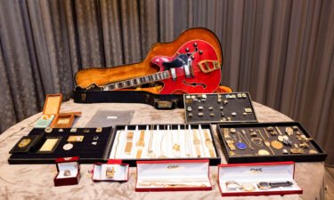A view of a guitar and a collection of personal jewelry of Elvis Presley & Colonel Tom Parker