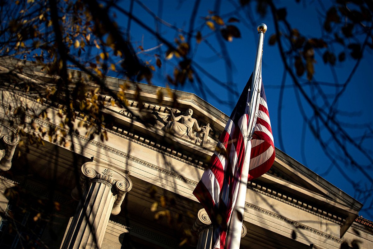 <i>Alexander Drago/REUTERS</i><br/>An American flag waves outside the Department of Justice Building in Washington in December 2020. The FBI's process for receiving reports of violent threats or harassment against election officials is not built to handle the volume of reports.