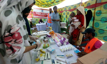 Displaced families wait to receive medicine at a distribution point in Sukkur