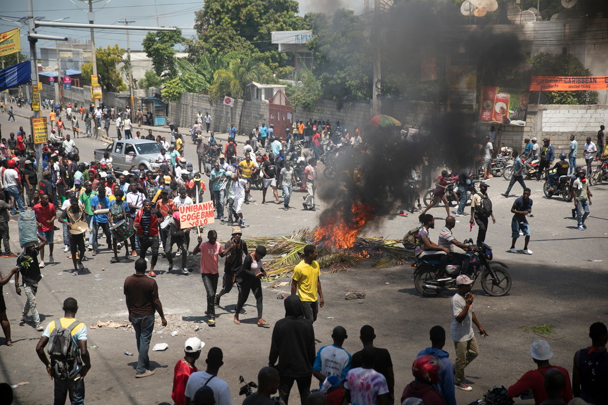 <i>Odelyn Joseph/AP</i><br/>People walk around burning tires set up by protesters during a protest to demand that Haitian Prime Minister Ariel Henry step down and a call for a better quality of life