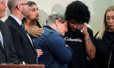 Donovan Lewis' mother Rebecca Duran is embraced as the police body camera footage of the deadly shooting is shown at a press conference.