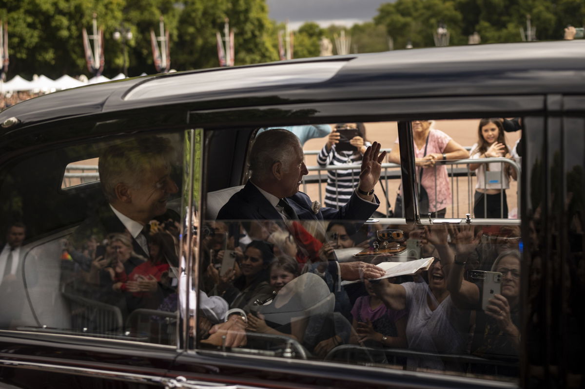 <i>Felipe Dana/AP</i><br/>King Charles III greets supporters as he arrives at Buckingham Palace.
