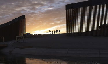 A pair of migrant families from Brazil pass through a gap in the border wall to reach the United States after crossing from Mexico to Yuma