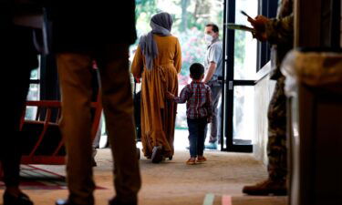 An Afghan national and her son walk through the National Conference Center (NCC)