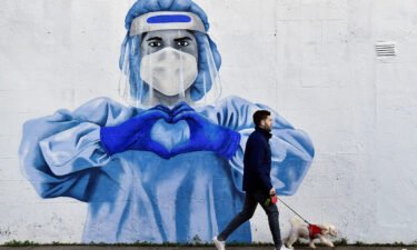 A man walks his dog past a mural depicting a frontline worker amid the spread of the coronavirus disease (Covid-19) in Dublin