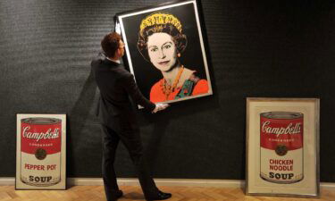 An employee of Bonhams Auctioneers adjusts a print by Andy Warhol of Queen Elizabeth II.