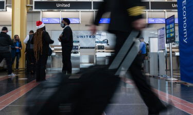 An airline crew member rolls their bag past the United Airlines ticket counter at Reagan National Airport in Arlington