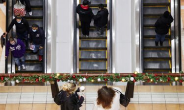 People ride an escalator while others stand at a mall during the holiday season shopping in Brooklyn