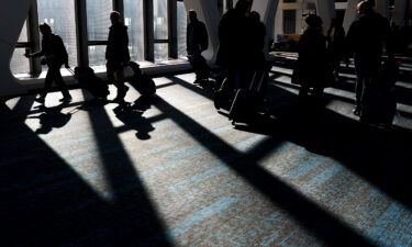 Travelers walk through LaGuardia Airport in New York on November 22. Travel experts say the ability of many people to work remotely is letting them take off early for Thanksgiving or return home later.