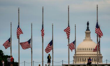 American flags are seen at half-staff surrounding the Washington Monument as people enjoy the weather on the National Mall on Wednesday