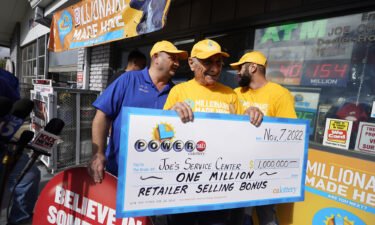 Business owner Joe Chahayed smiles as he holds a check with his sons