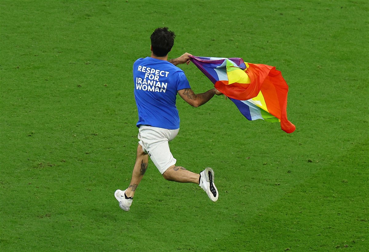 <i>Molly Darlington/Reuters</i><br/>A pitch invader runs onto the pitch wearing a t-shirt with a message saying: 'Respect for Iranian Woman' on the back and holding a rainbow flag.