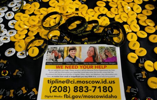 A flyer seeking information about the killings of four University of Idaho students is displayed on a table along with buttons and bracelets