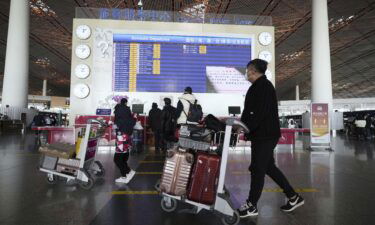 People walk with suitcases through a departure lobby the Beijing airport on December 27.