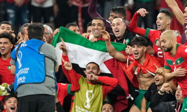 Morocco's team poses with the Palestinian flag after beating Spain on December 6.