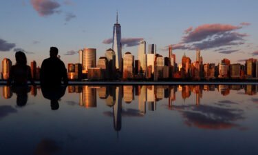 The skyline of lower Manhattan and One World Trade Center is reflected in the top of a monument as the sun sets in New York City on June 19