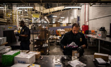 Customs and Border Protection Officer Mohammed Rahman holds a bag filled with white powder for testing at the JFK International Mail Facility in 2018