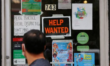 Economists are betting that the labor market cooled in December. A pedestrian passes a "Help Wanted" sign in the door of a hardware store in Cambridge