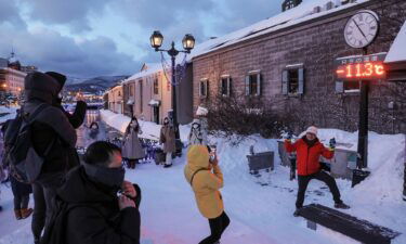 Tourists pose for photos in front of a thermometer reading -11.3 degrees Celsius (11.6 F)